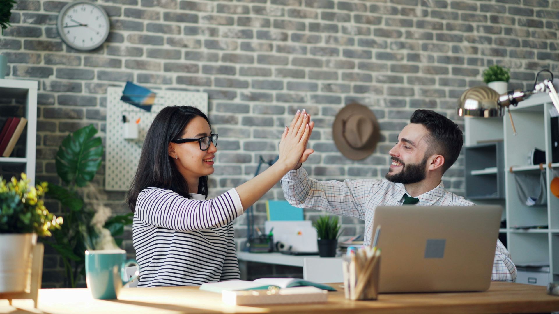 Two people in a mentorship meeting, high-fiving each other.
