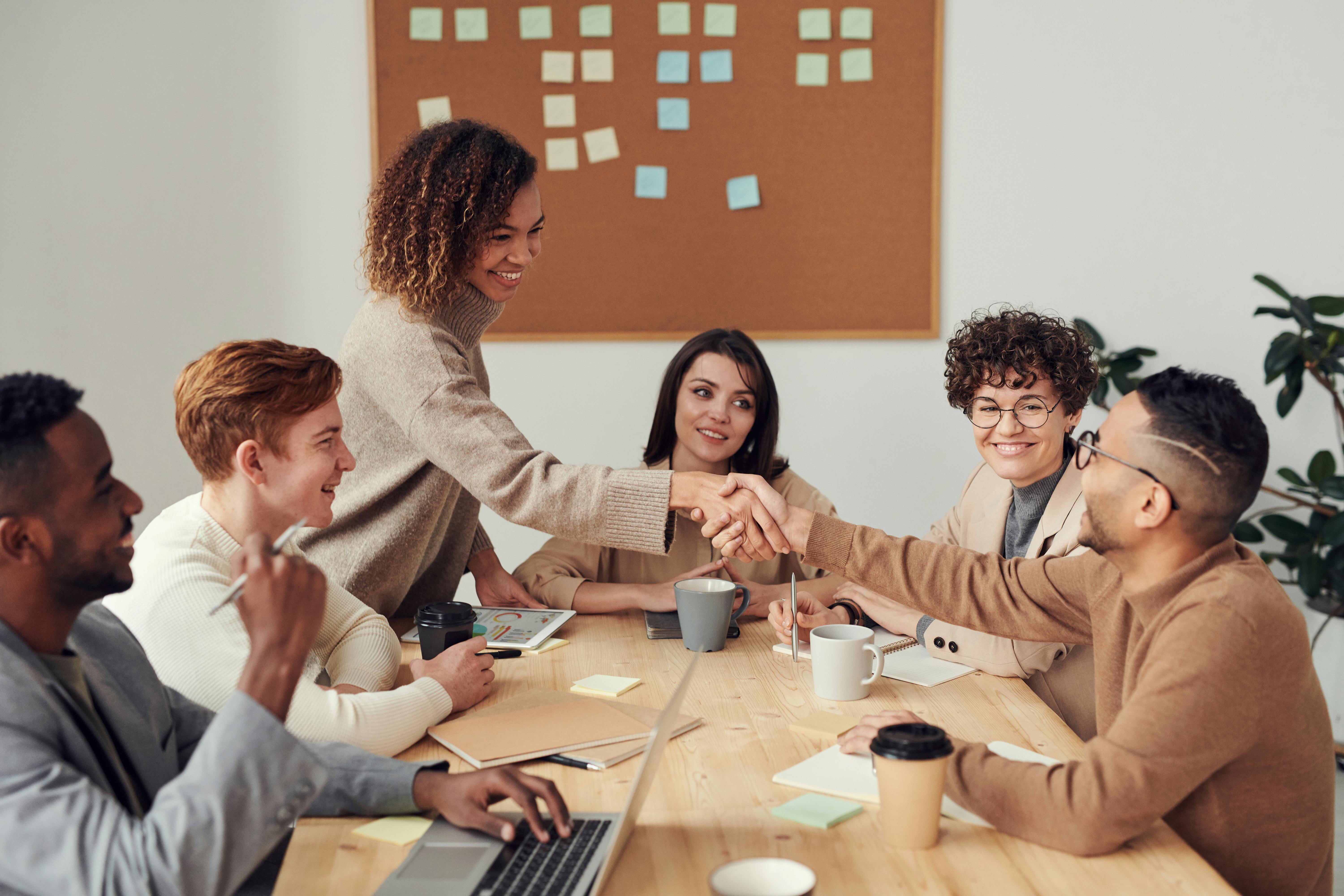 Group of people smiling at a table and two are shaking hands